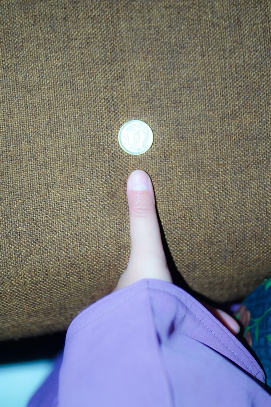 Hand shot from too far away with the coin sitting well away from the thumb — nail and coin both too small to measure